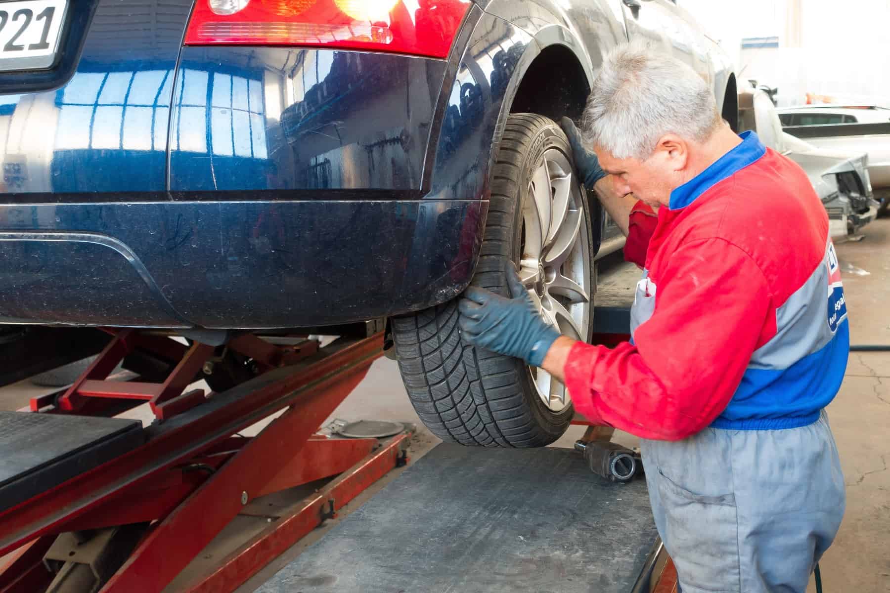A man repairing a the rear tire of a car